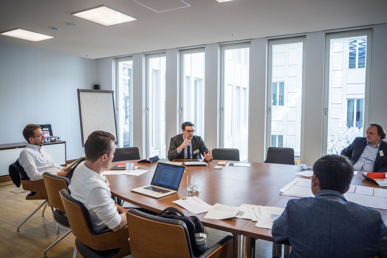 Teilnehmer und Teilnehmerinnen sitzen an einem Arbeitstisch