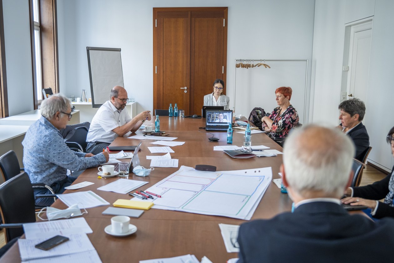 Teilnehmer und Teilnehmerinnen sitzen an einem Arbeitstisch