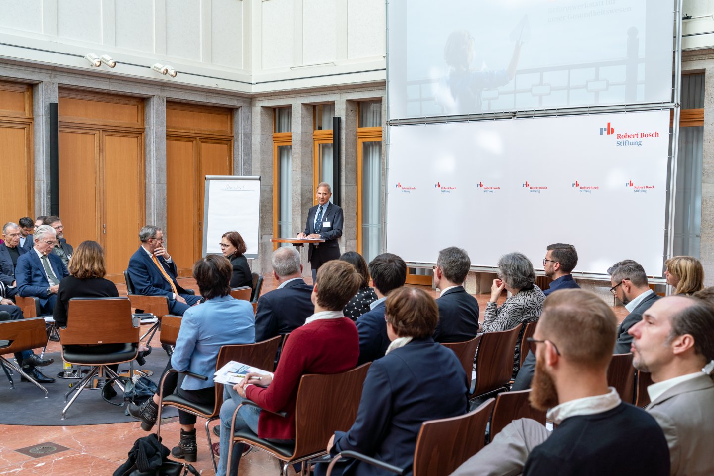 Besucher des ersten Podiums hören sich die Eröffnungsrede an