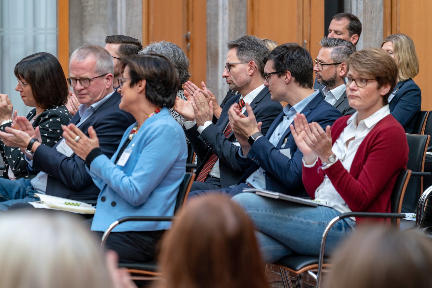 Besucher des ersten Podiums applaudieren nach der Eröffnungsrede